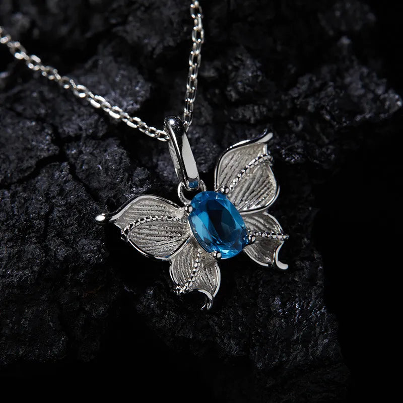 Angled view of Natural Blue Topaz butterfly necklace with textured sterling silver wings