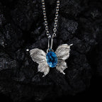 Natural Blue Topaz butterfly pendant necklace displayed on black rock