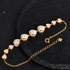 Gold-tone heart link bracelet with ten hearts set with round moissanite stones on a black textured background