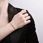 Gold-tone moissanite heart bracelet worn on the wrist against a black blazer