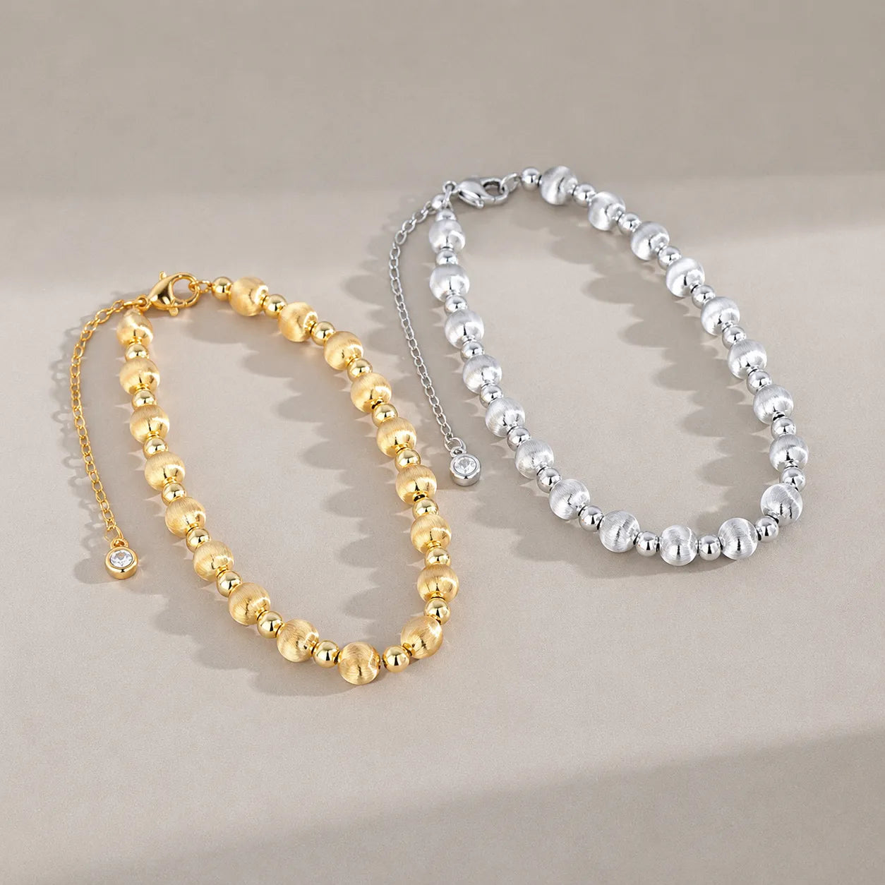 Silver and gold-color round bead bracelets displayed side by side with extender chains