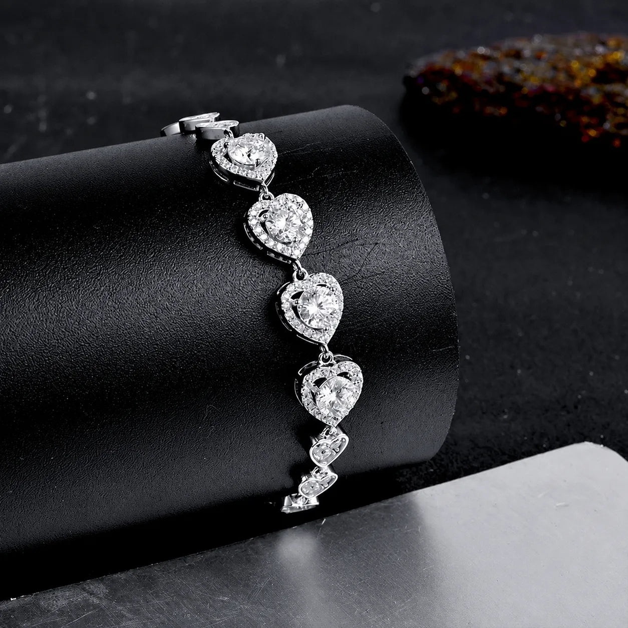 Close-up of four larger hearts set with round moissanite stones on the silver bracelet