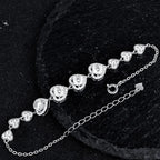 Silver heart link bracelet with a spring ring clasp and extender chain on a black textured background