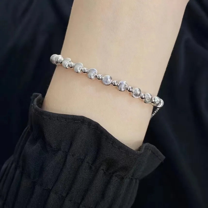 Silver round bead bracelet with alternating brushed beads and polished spacers worn on the wrist