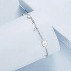 Silver sun bracelet detail with a fixed round medallion and smaller hanging motif